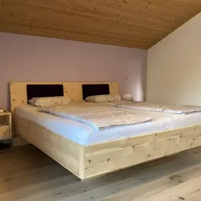 Modernes Schlafzimmer mit Doppelbett aus Holz, Holzdecke und minimalistischer Einrichtung.